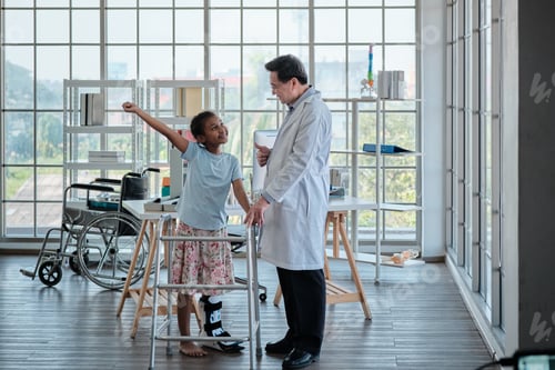 Preview: Asian doctor helping disabled Black girl to walk in an orthopedic hospital.
