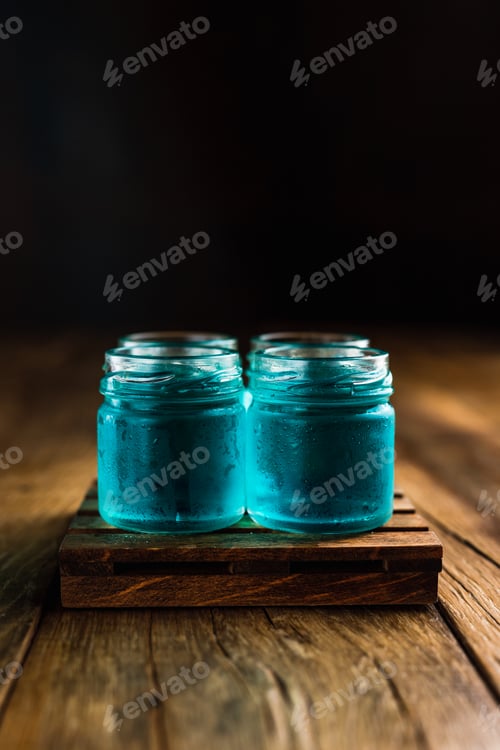 Preview: Blue colored alcoholic shooters, or shot drinks on wooden table, with copy space