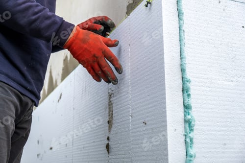 Preview: Construction worker installing styrofoam insulation sheets on house facade wall