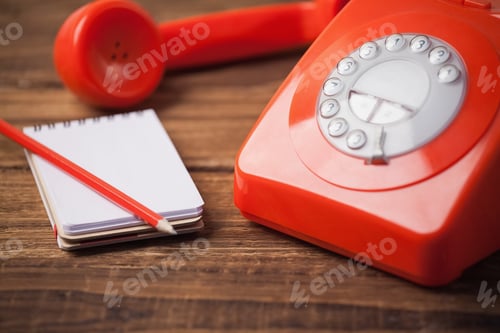 Preview: Red telephone on wooden table with notepad