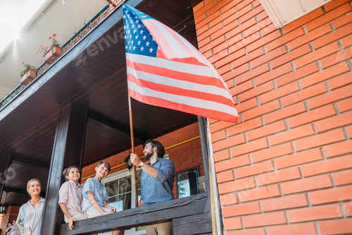 Preview: family with american flag standing on country house porch