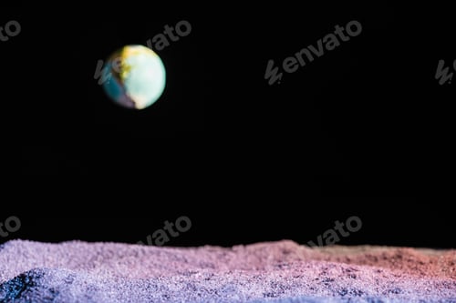 Preview: sandy ground with blurred planet Earth in space isolated on black with copy space