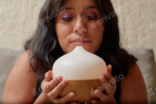 Preview: Young Latina woman reads a book while using aromatherapy.