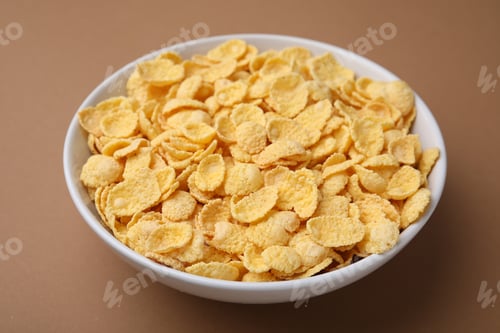 Preview: Breakfast cereal. Tasty corn flakes in bowl on brown table, closeup