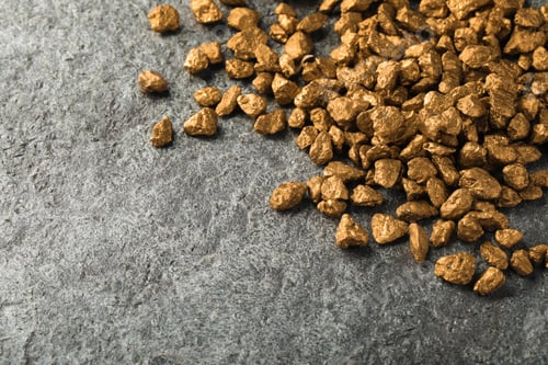 Preview: Pile of gold nuggets on grey table, space for text