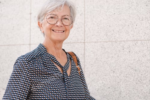 Preview: Beautiful caucasian senior woman walking down the city street looking at camera smiling