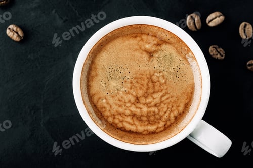 Preview: A Close-Up View of Freshly Brewed Coffee in a White Mug Surrounded by Coffee Beans on a Dark Surface
