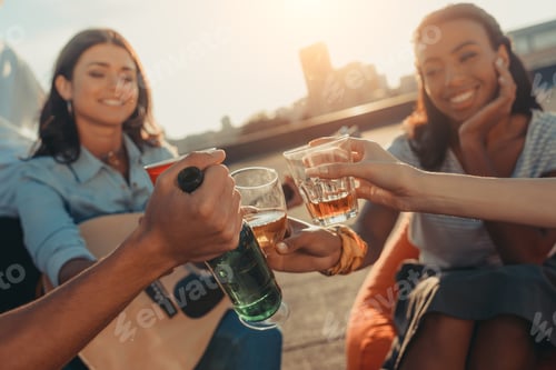 Preview: close-up shot of friends clinking glasses on roof party
