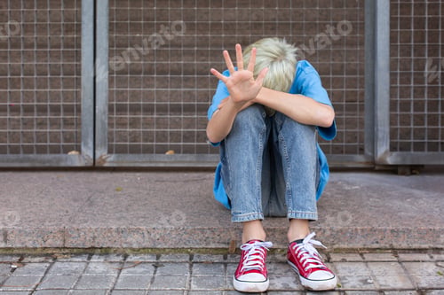 Preview: Lonely teenager showing a stop sign sitting on the floor
