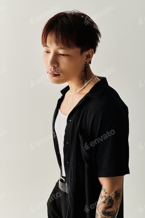 Preview: Stylish young Asian man posing confidently in minimalist studio during bright daylight