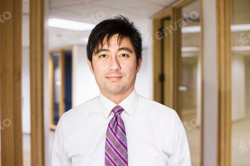 Preview: A portrait of an asian businessman standing alone in his office space.