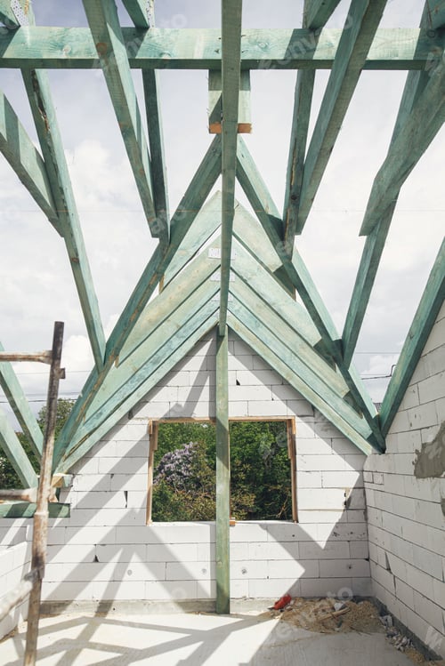 Preview: Unfinished roof trusses, view in attic with rafters and beams against sky