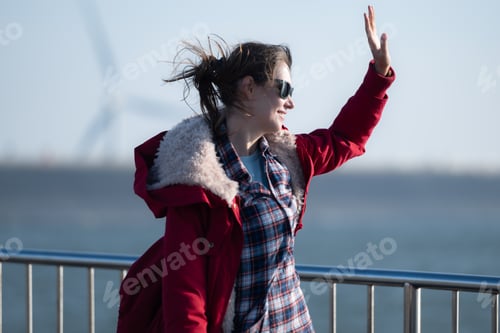 Preview: On the background of windmills, A young woman in a red jacket is enjoying her winter vacation.