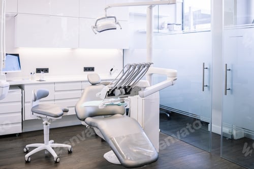 Preview: Leather dental chair with various medical instruments located in white dentist office.