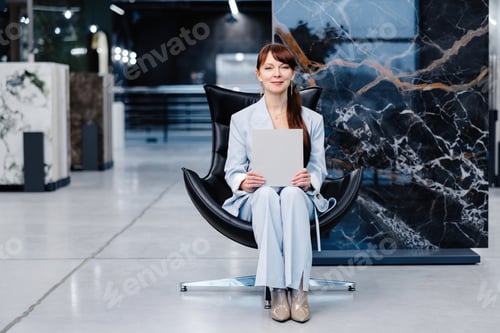 Preview: Woman holding blank paper sitting in chair in showroom