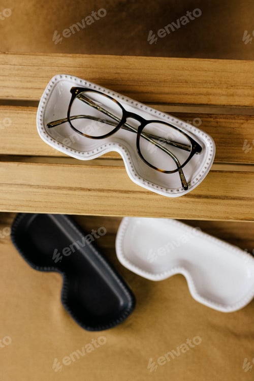Preview: Vertical shot of eyeglasses and black and white cases on a wooden surface