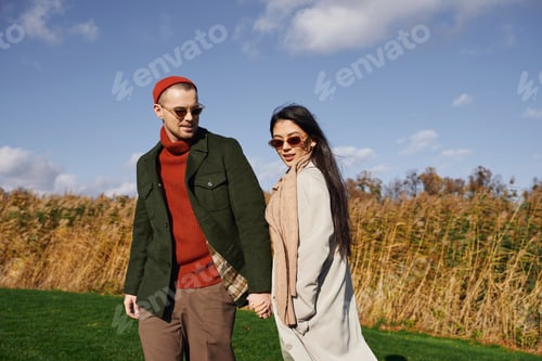 Preview: A delightful couple enjoys a sunny autumn walk among golden fields in cozy attire