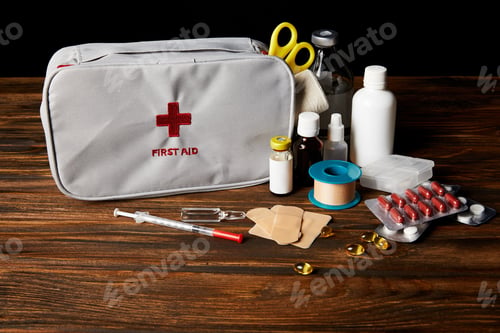 Preview: close-up shot of first aid kit with different medicines on wooden tabletop and on black