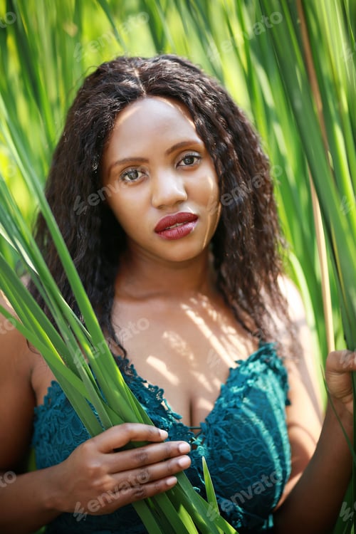 Preview: Cheerful young Afro American woman standing in tropical garden.
