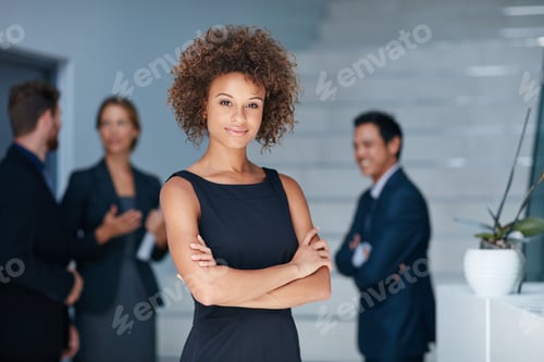 Preview: Portrait of a young businesswoman standing in an office with colleagues in the background