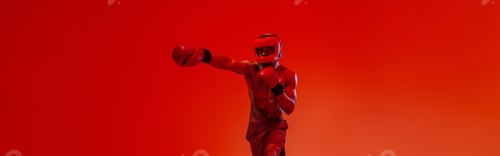 Preview: Sporty man wearing head guard and boxing gloves practicing for fight on studio background