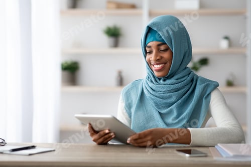Preview: Young Black Muslim Lady In Hijab Using Digital Tablet At Home Office