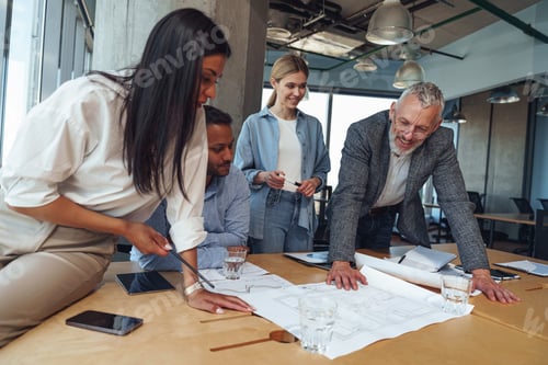 Preview: Team of focused professional design engineers working with project documents in modern office