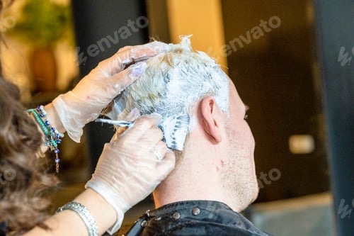 Preview: Hairdresser applying dye to client's hair