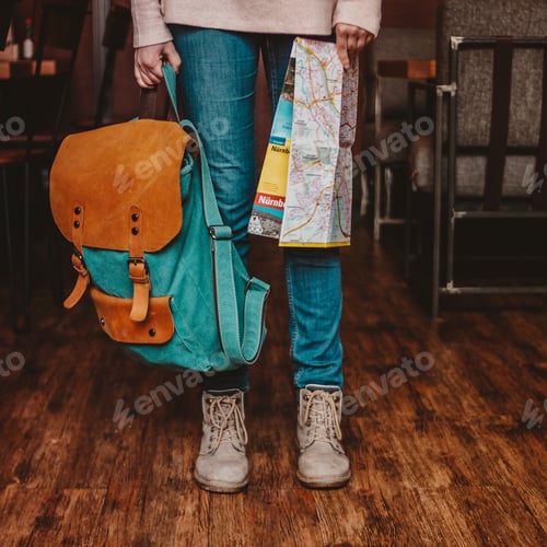 Preview: Crop photo of young woman feet girl traveler in jeans and boots with backpack and map indoors