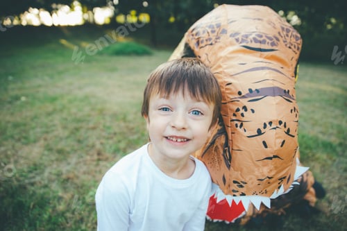 Preview: Father and son playing at the park, with a dinosaur costume, having fun with the family outdoor