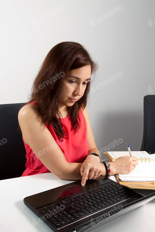 Preview: Woman Working on Laptop and Writing in Notepad