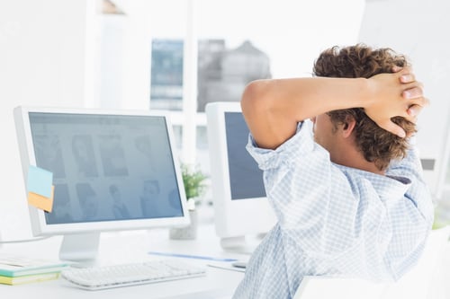 Preview: Rear view of a casual young business man using computer in a bright office