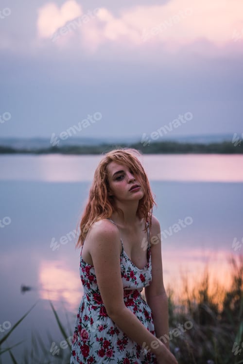 Preview: Beautiful woman in dress on lake shore in sunset