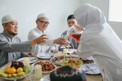 Preview: Young Muslim Woman Pouring Tea Into The Glass During Eid Celebration At Dining Room