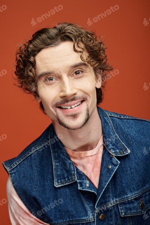 Preview: Handsome Man Smiling Against Vibrant Orange Backdrop in Artistic Portrait