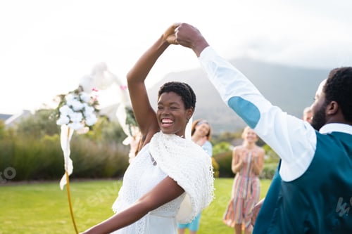 Preview: Happy african american couple holding hands and dancing during wedding