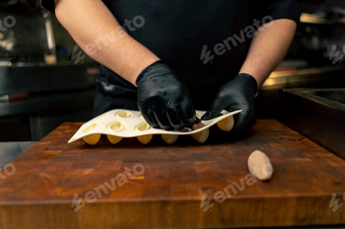 Preview: close-up in a professional kitchen hands in black gloves take a delicacy out of a silicone mold