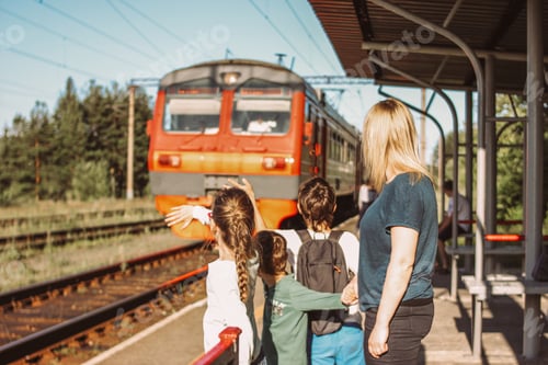 Preview: Group of children tweens from behind with mom invite train on the old railway
