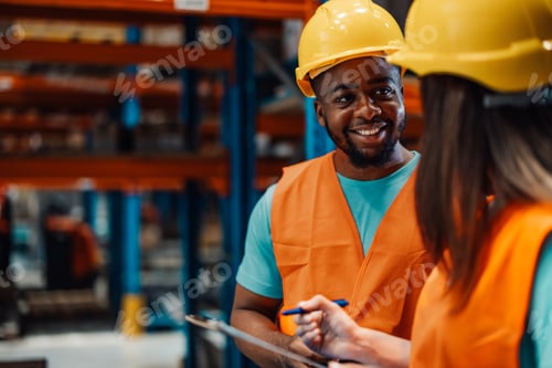 Preview: Smiling black male worker engaging with colleague in industrial area