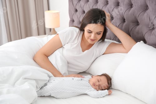 Preview: Happy woman with her sleeping baby on bed