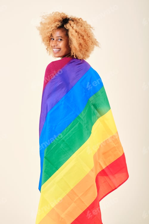 Preview: Happy afro woman wrapped with a gay pride flag on an isolated background.
