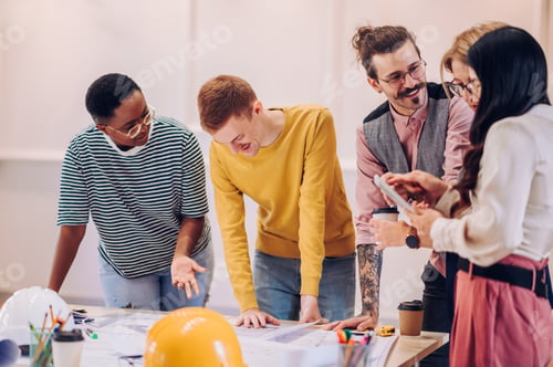 Preview: Multiracial team of architects having a meeting while using blueprints
