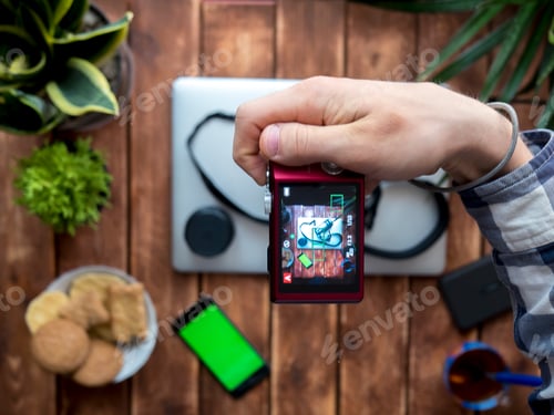 Preview: overhead photographer making photo with compact camera at home above the table