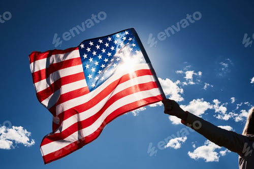 Preview: Waving usa flag in hand against blue sky