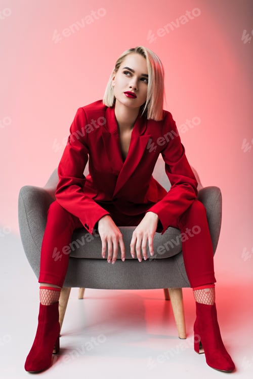 Preview: elegant stylish woman in red clothes posing in armchair, on pink