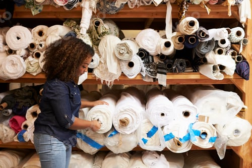 Preview: Mixed race woman selects fabric at a clothing design studio