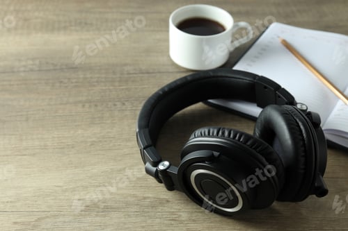 Preview: Black big headphones, on a table with a notebook and coffee.