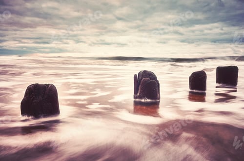 Preview: Color toned picture of an empty beach with blurred water.