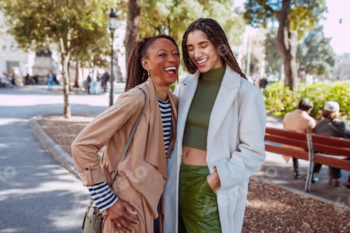 Preview: Two happy women laughing together in a city park