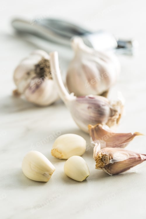 Fresh Garlic Bulbs and Cloves on White Surface